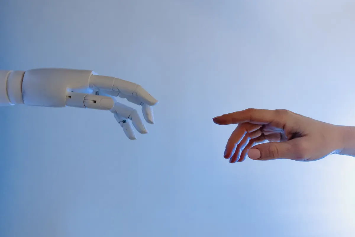 人間の手がロボットの手に向かっている。これは技術とつながりを象徴している。