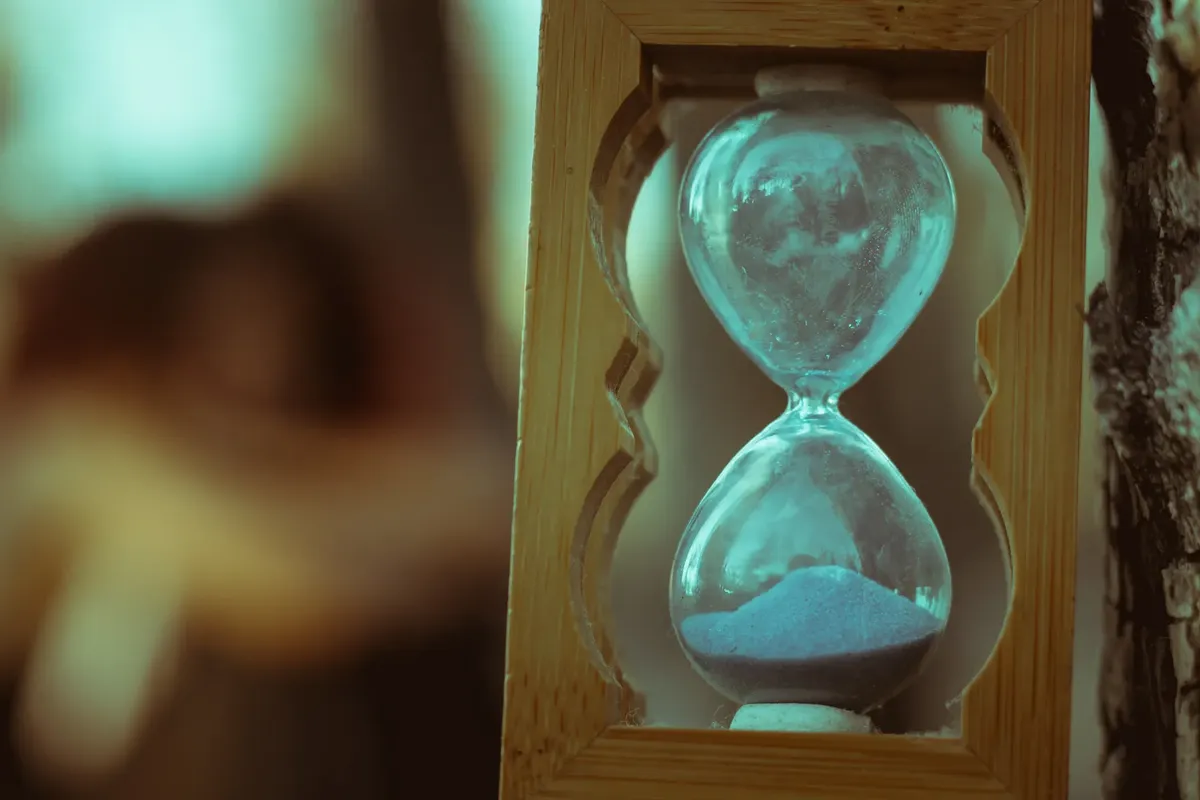 Glass bulbs of hourglass filled with sand framed in wood and placed in nature