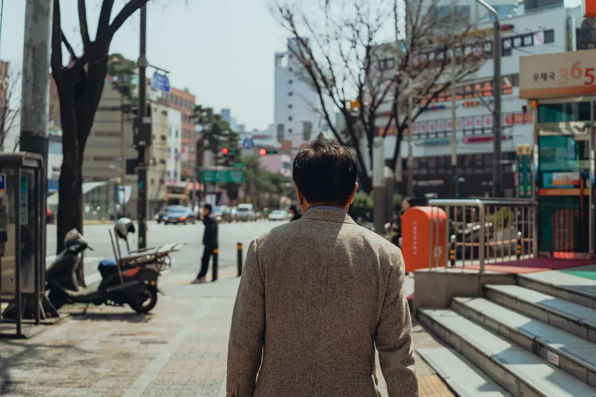 Street photography capturing a man walking in a busy Seoul street during daylight.