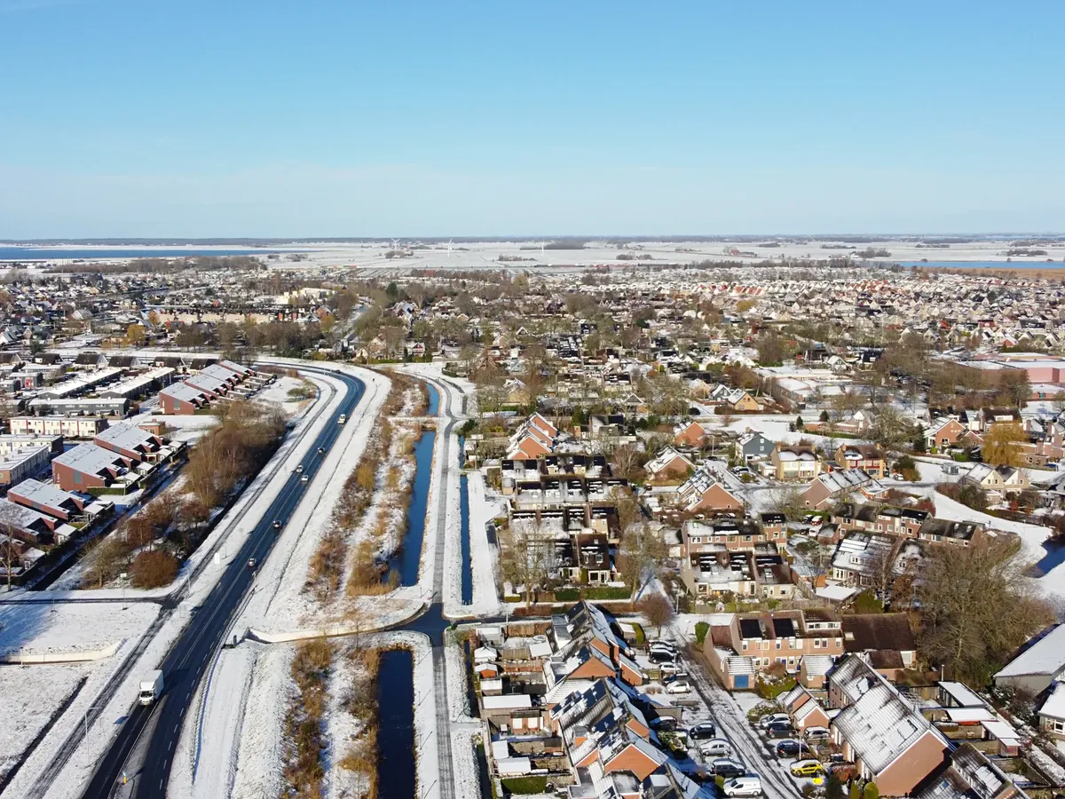 Aerial view of a suburban residential district covered in snow, showing roads, houses, and urban planning.
