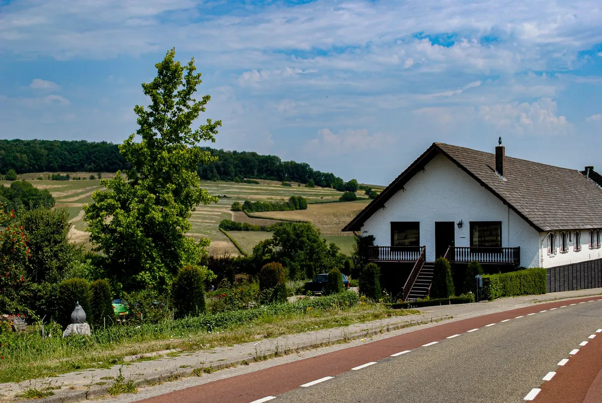 Picturesque rural landscape with a white house and lush green fields under a clear blue sky.