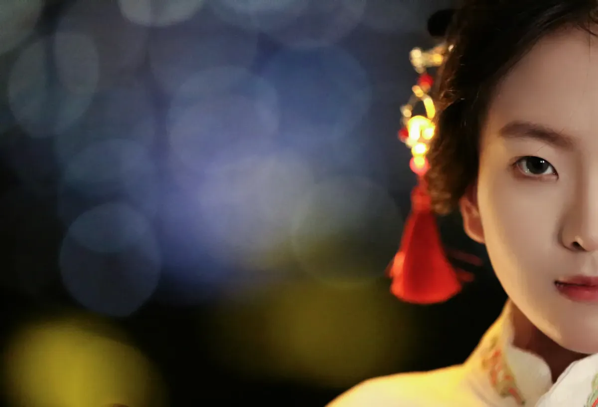 Half portrait of a woman in traditional Asian clothing with soft focus bokeh lights.
