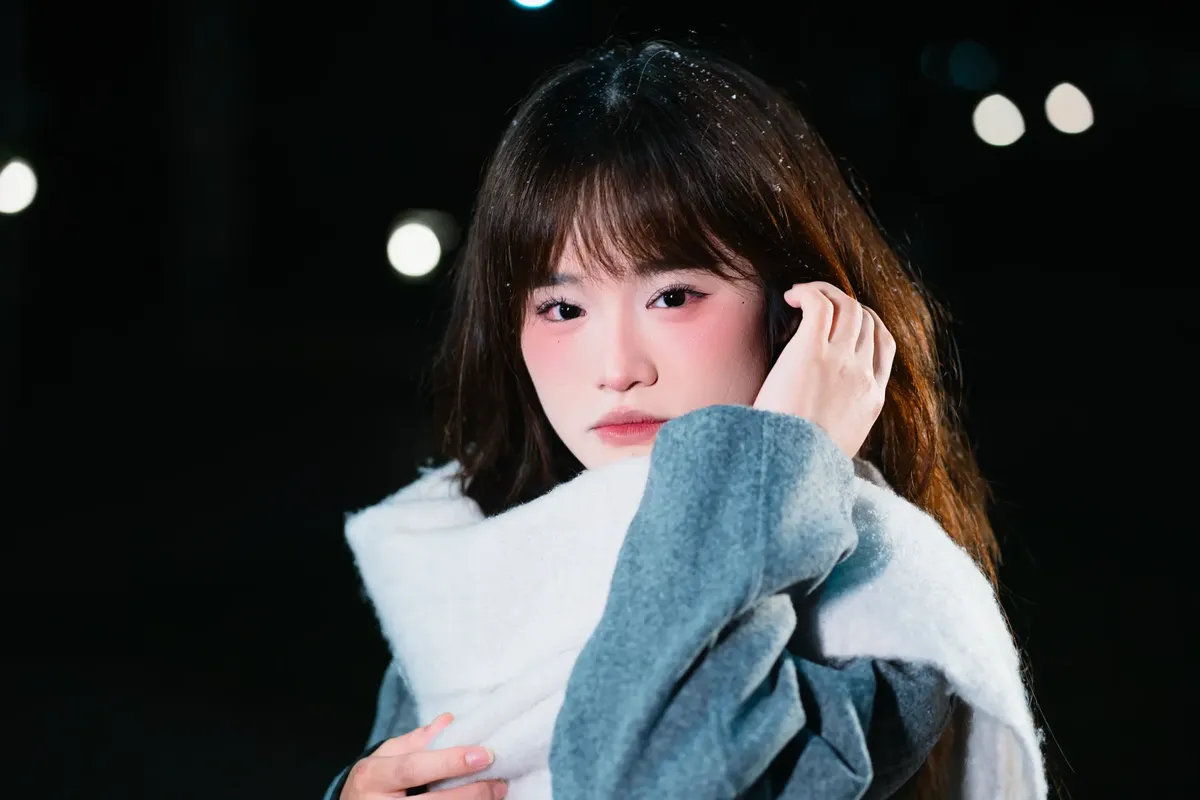 Stylish woman wrapped in scarf at night, capturing a thoughtful expression.