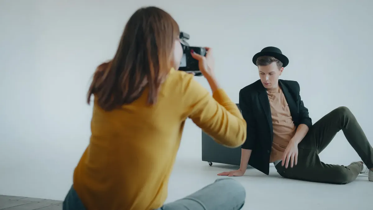 A fashion photographer captures a male model in a sleek outfit at a studio setting.