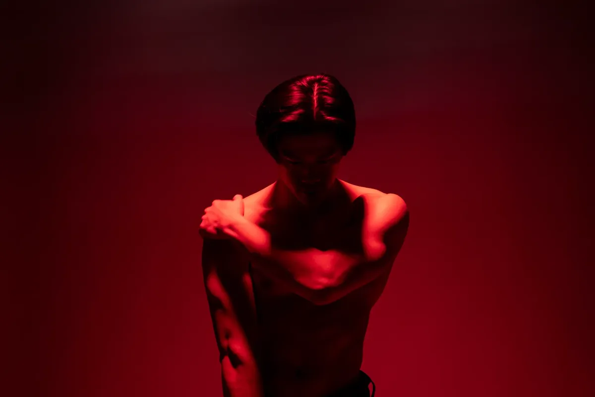드라마틱한 빨간 조명 아래 아름다운 어두운 그림자로 구성된 남자의 예술적인 포토그래프.