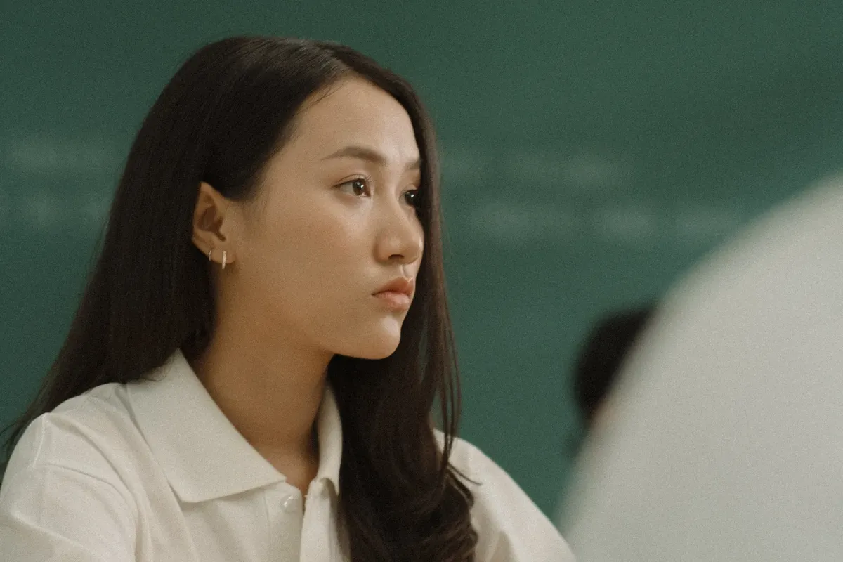 Close-up of a young woman in a classroom setting, displaying focus and attentiveness.