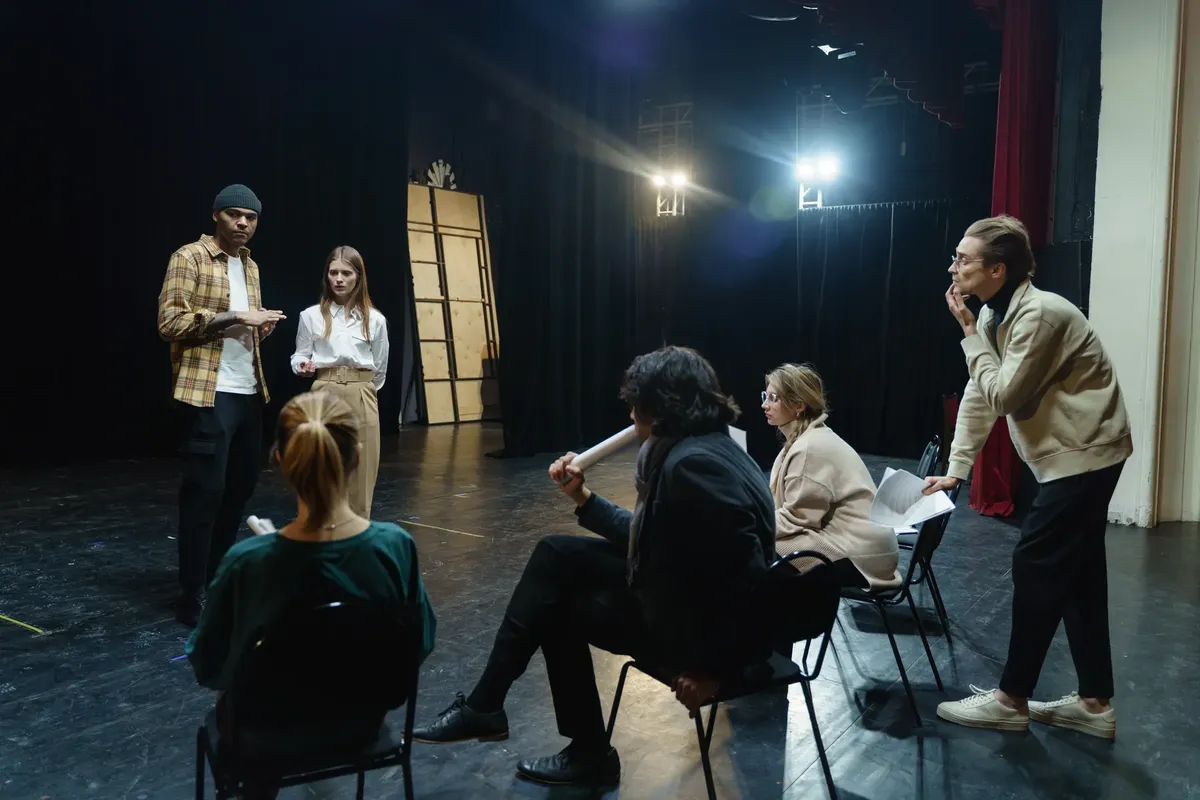 Actors rehearsing on stage with director's guidance in a theater for a live performance.