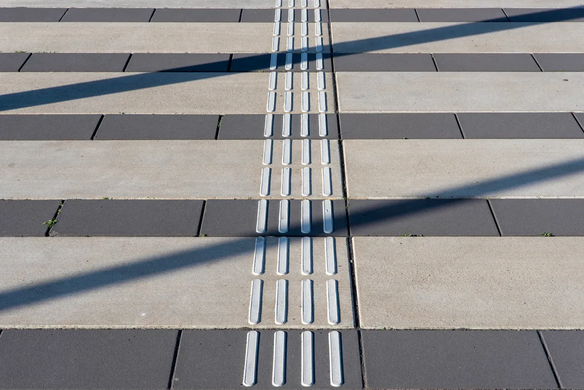 Tactile paving guiding visually impaired pedestrians on an urban sidewalk.