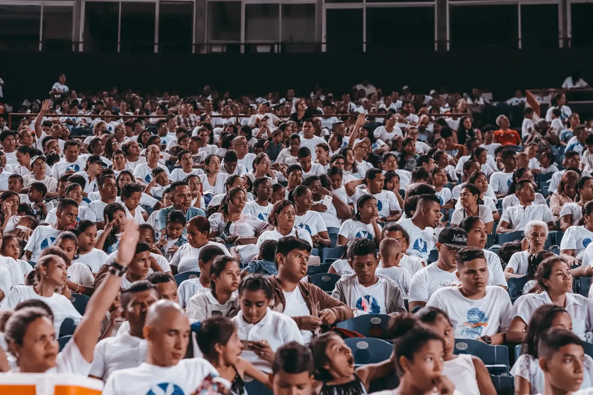 A diverse crowd in matching shirts at a stadium event indoors.