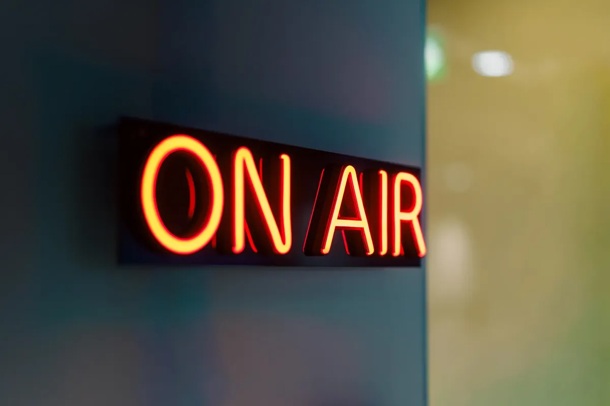 어두운 라디오 스튜디오에서 반짝이는 'On Air' 노인 신호등의 줄거리가 있는 근접 촬영.