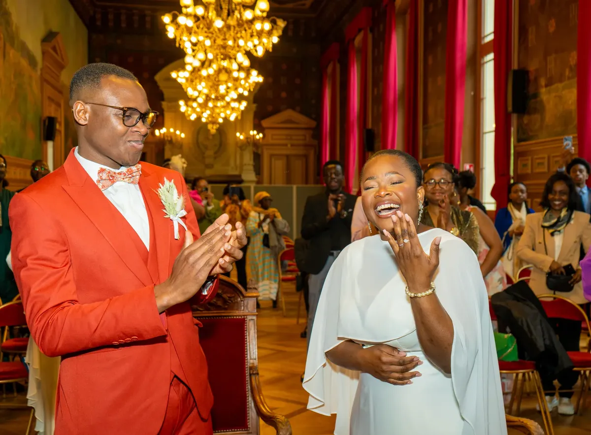 A joyful moment captured during an elegant African wedding ceremony indoors with friends and family.