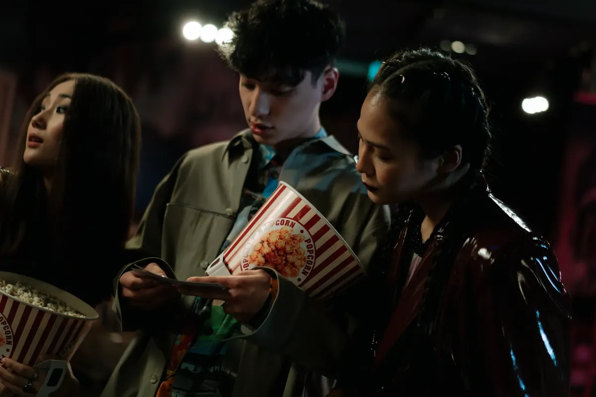 Group of friends enjoying popcorn indoors during a movie night, creating a cozy atmosphere.