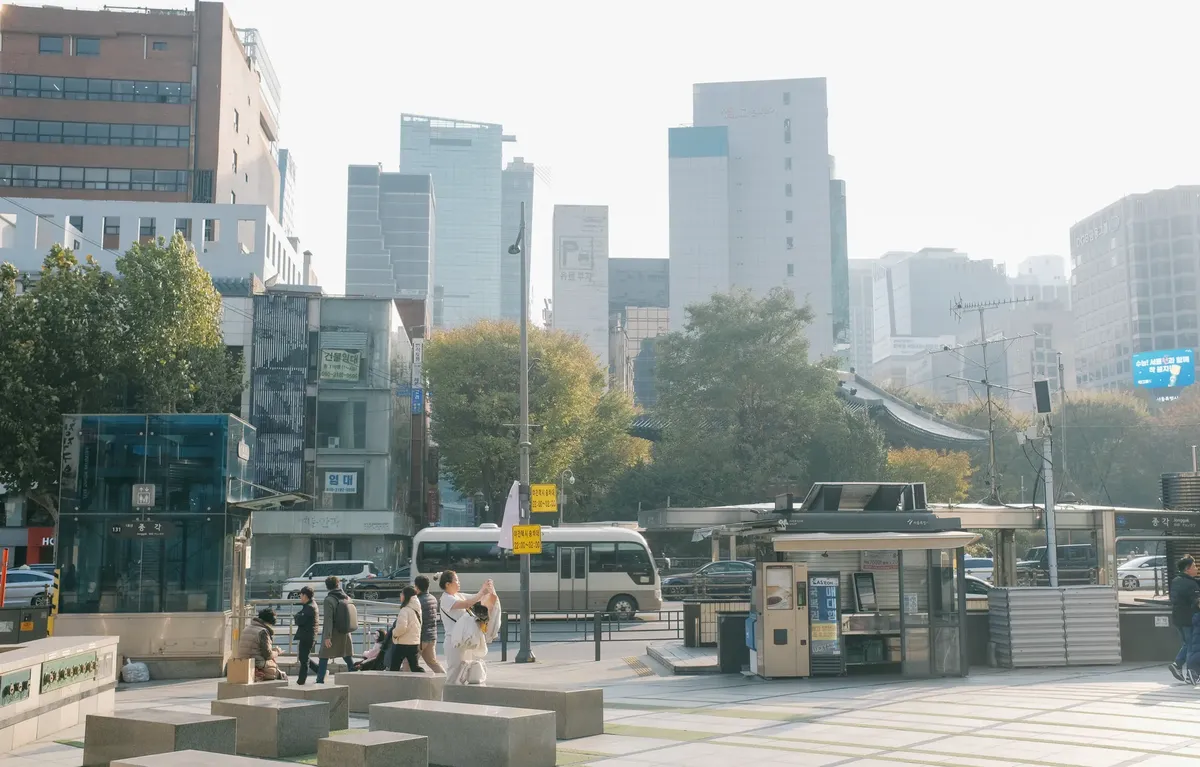 Vibrant scene of Seoul city with skyscrapers and pedestrians on a sunny day.