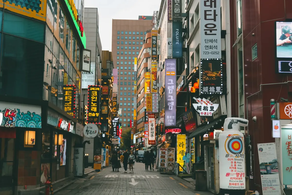 Bustling street in Seoul with vibrant signs and people walking. Captures urban life in South Korea.