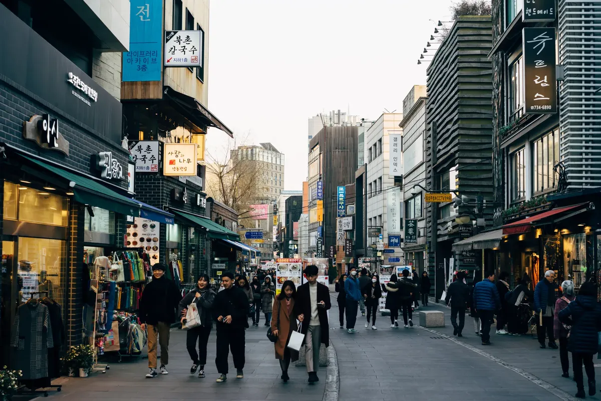 Lively shopping street in Seoul with people walking, shops, and vibrant city life.