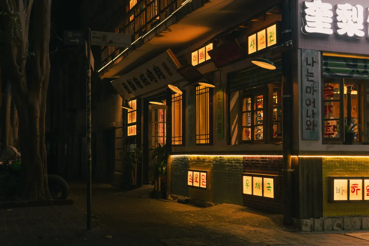 A cozy Korean restaurant with warm illuminated signs at night, perfect street photography.