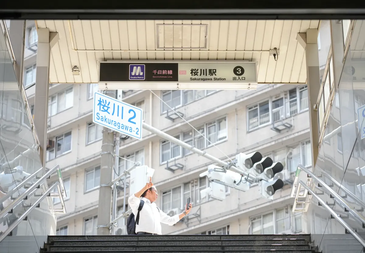 大阪のサクラガワ駅入口の様子。その場所で someone が自撮りをしている。