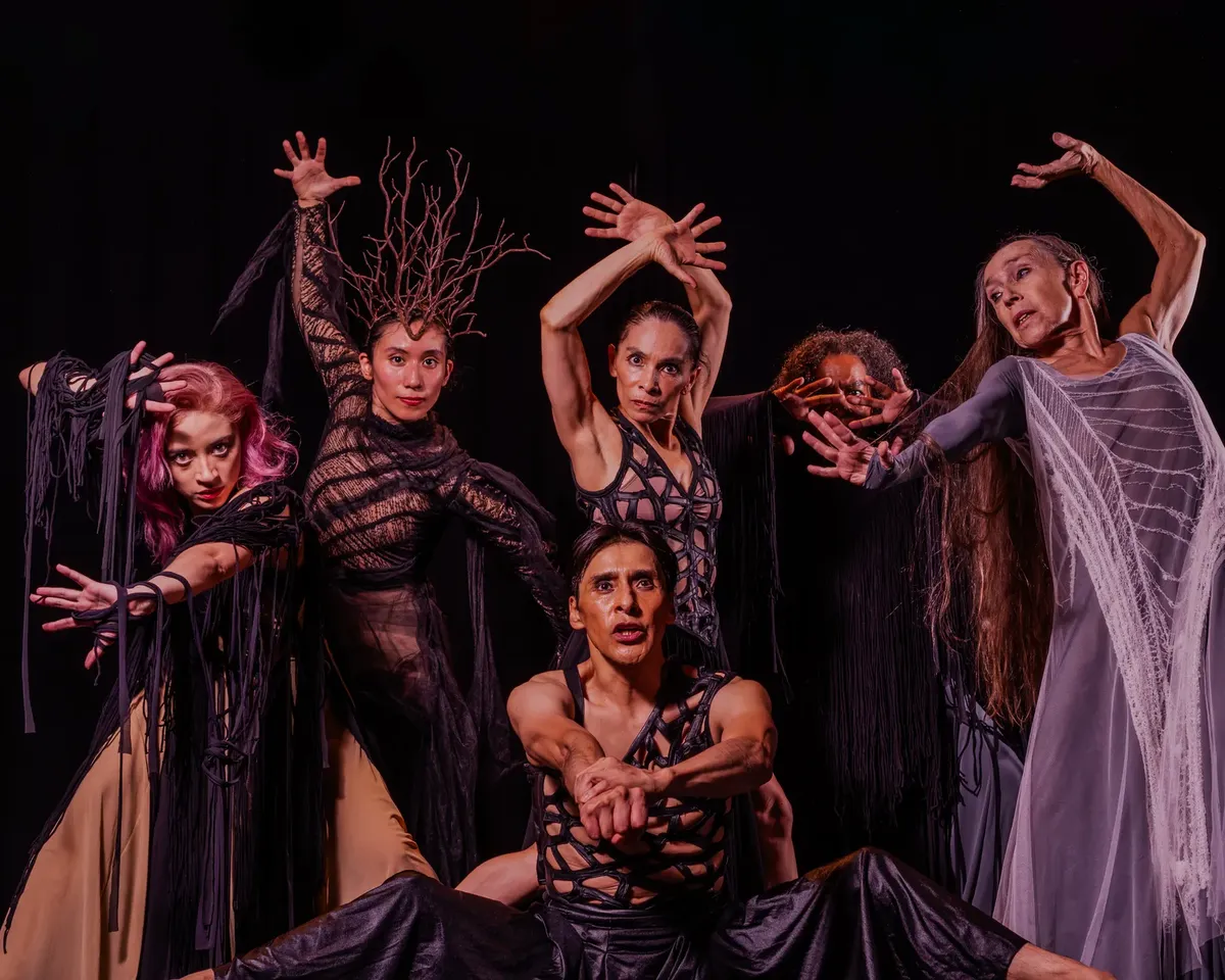 Vibrant group portrait of dancers in expressive poses on stage, showcasing emotion and drama.