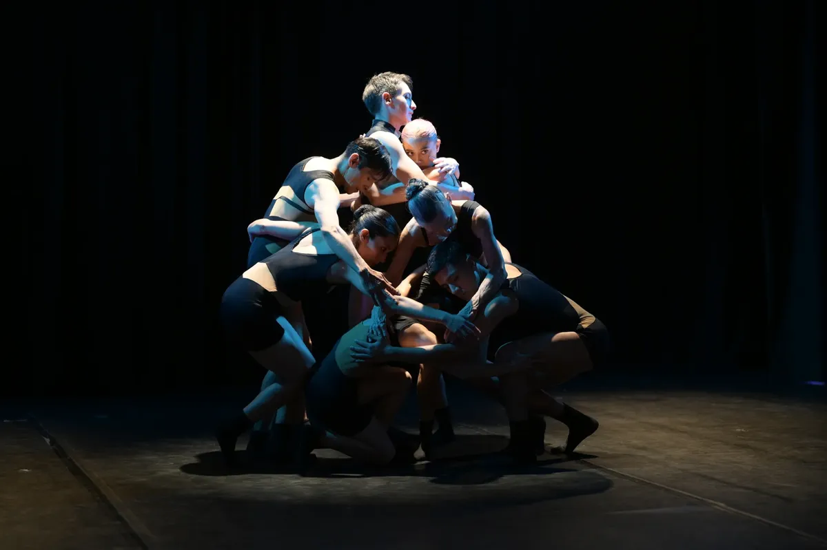Dancers performing a dramatic piece on stage in a theater setting.