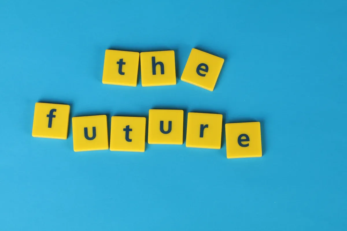 Yellow letter tiles spelling 'the future' on a blue surface, minimalist style.