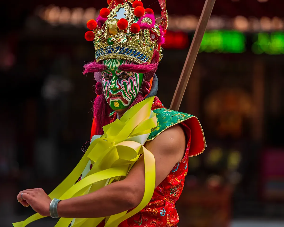 一名活躍的文化表演者，臉上塗有複雜的臉譯與服裝，於台灣祭典期間拍攝.