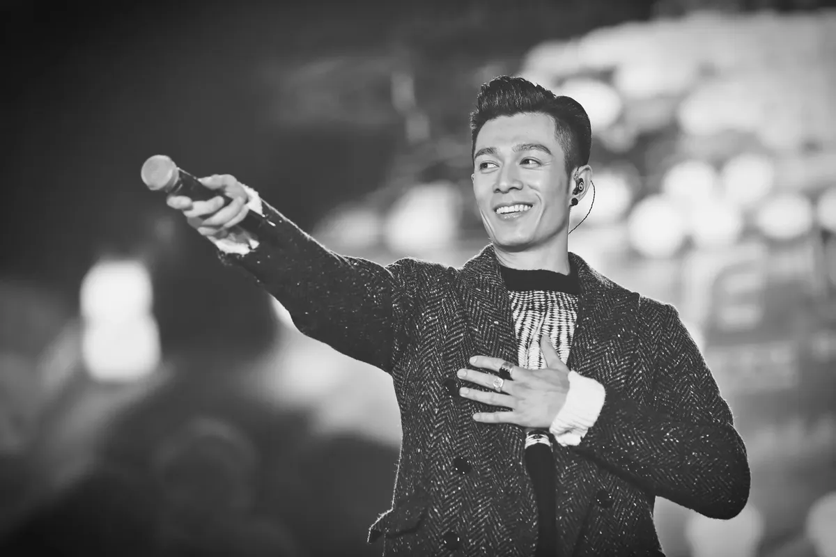 Monochrome photo of a singer enthusiastically performing live on stage.