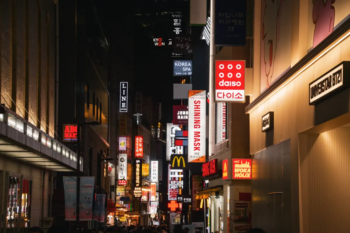 首爾繁華購物區的動態夜景， showcasing 各種商店標誌與都市燈光。