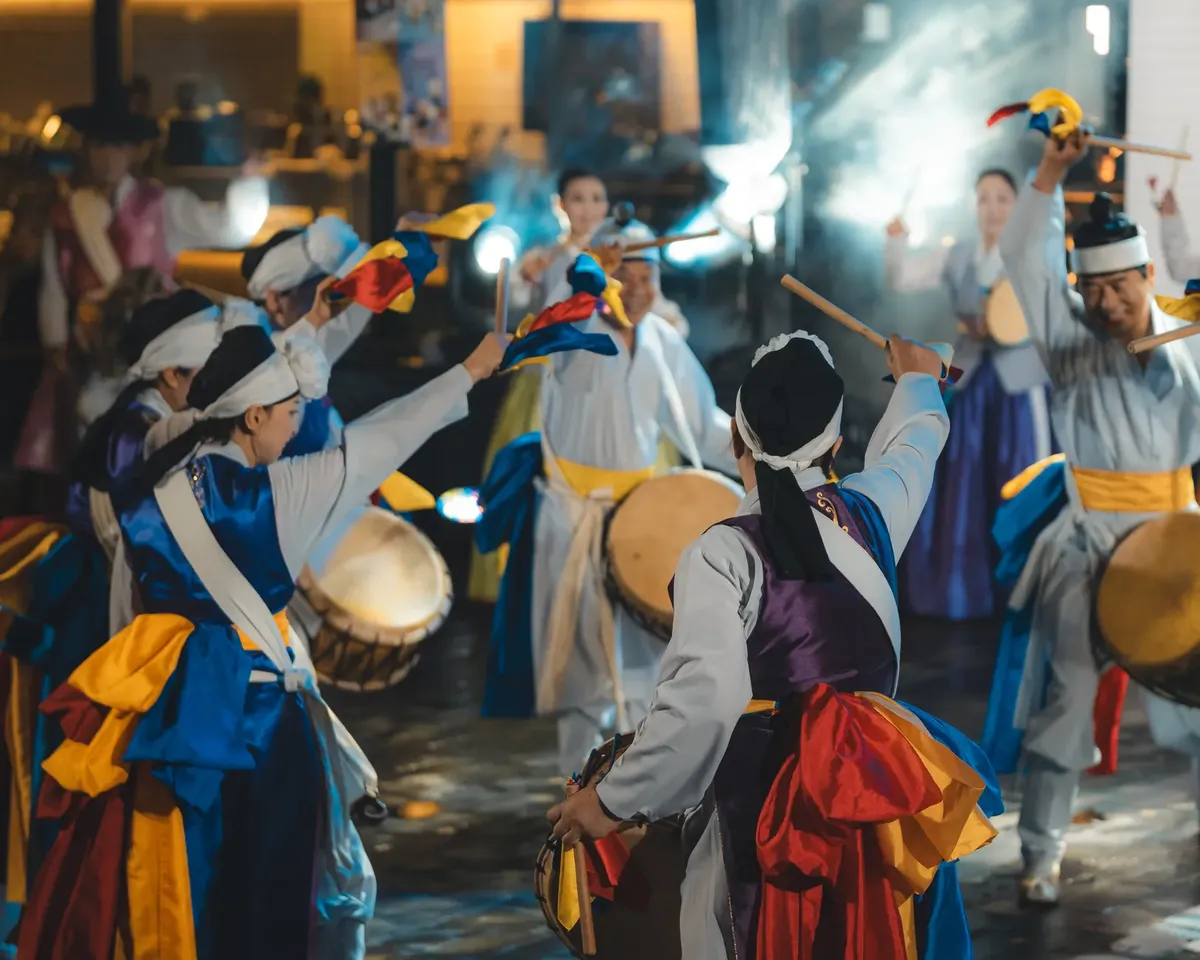 Group performing a vibrant traditional Korean dance outdoors with colorful costumes and drums.