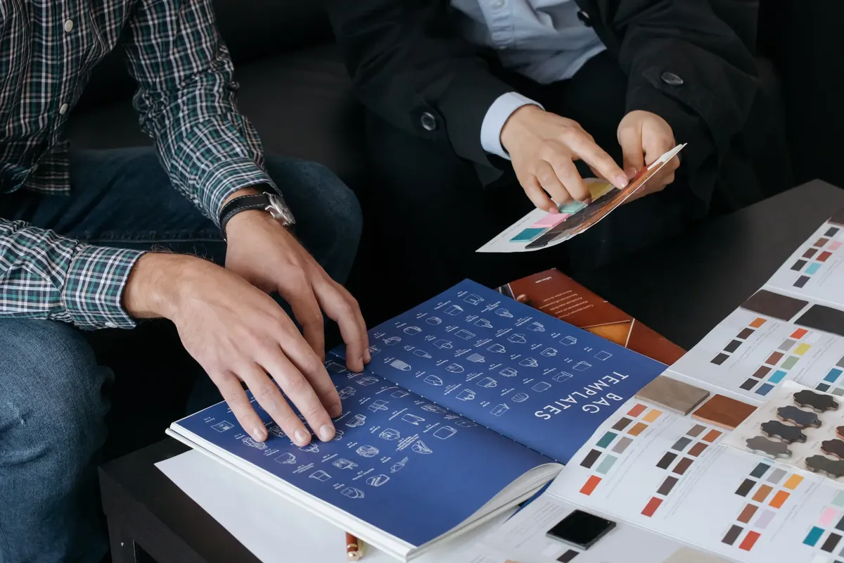 Close-up of designers reviewing bag templates and color swatches at a workspace.