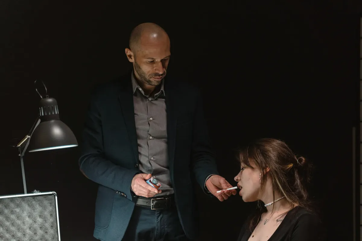Intense interrogation scene featuring a man and woman under a dim light.