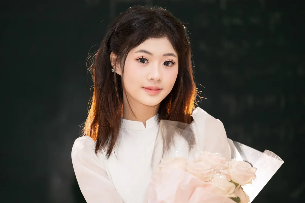 Portrait of a young woman in Hà Nội wearing traditional dress holding roses.