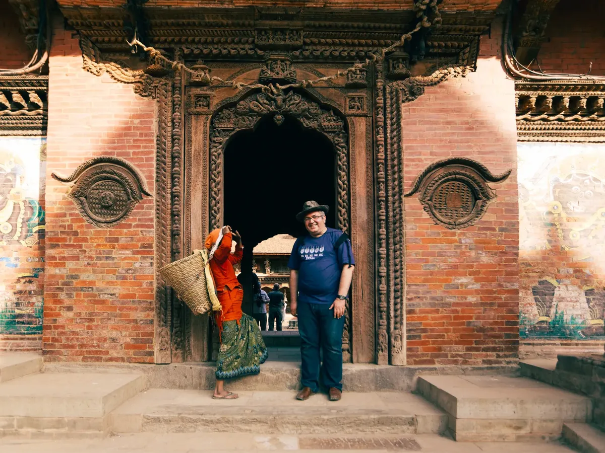 A man and a local woman at a historic brick entrance with detailed carvings.