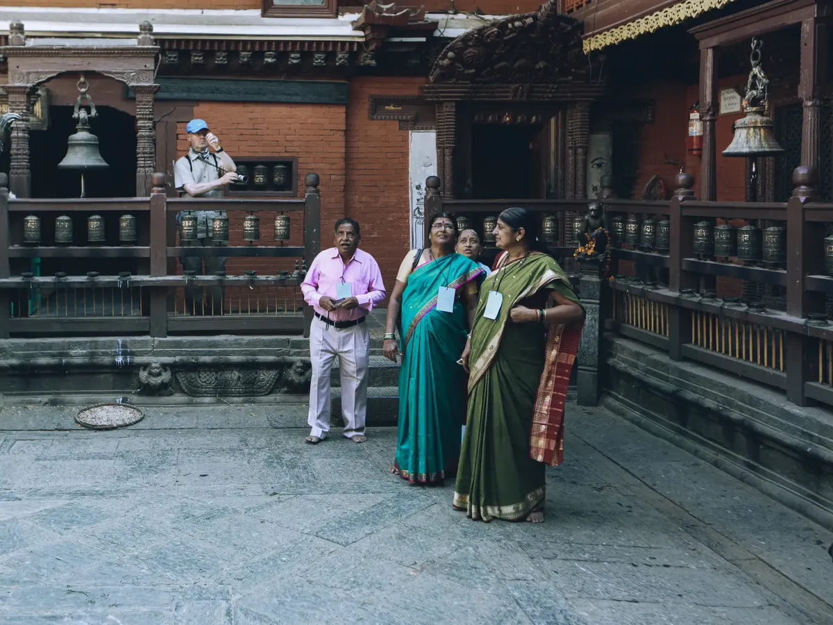 Tourists in traditional attire at a historic temple with ornate architecture.