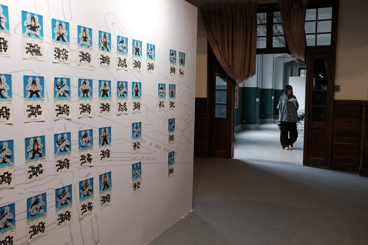 室內藝術展覽，展示照片在白色牆壁上，背景有個人