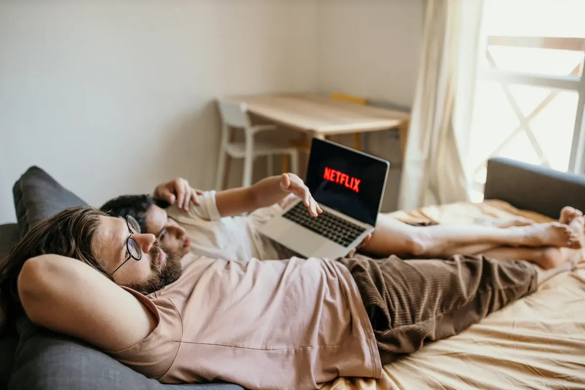 A couple lounging on bed watching Netflix, creating a cozy indoor atmosphere.